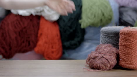 female hand takes coil of wool from table