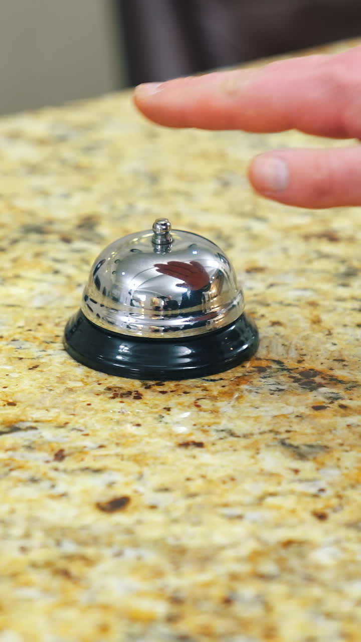 Bell on reception at the hotel to call the administrator. Beautiful blurred background. The hand of the man who presses the call. Concept for hotels. Vertical video