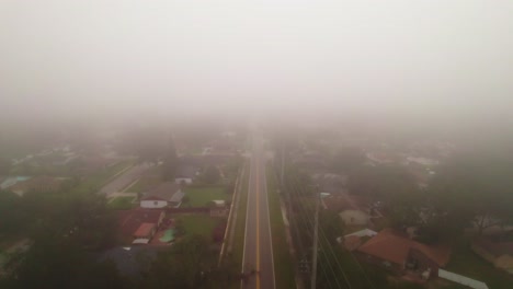 aerial flyover of foggy and misty road through city of ocoee, florida with no vehicle driving