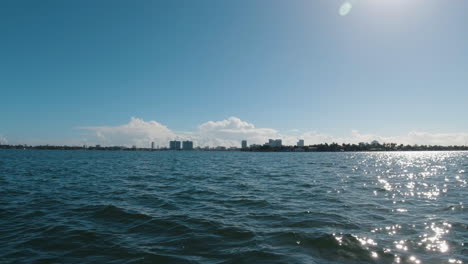 speeding along the water toward a city on the horizon from the pov of a small boat