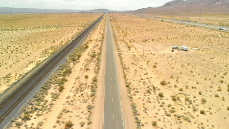 aerial jib up of empty desert road near highway and railroad tracks