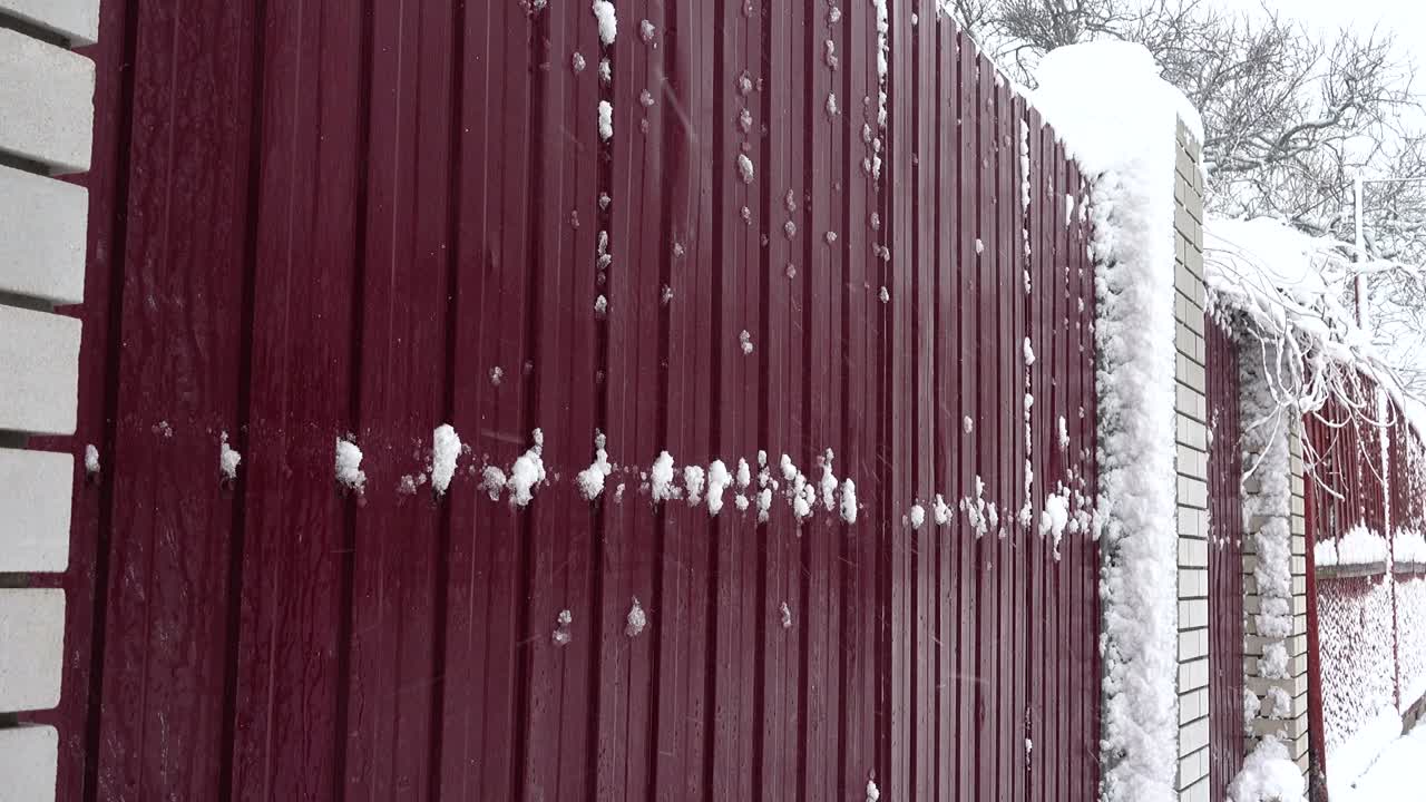 Snow against the background of a fence. Snow in the city. Shooting in the winter