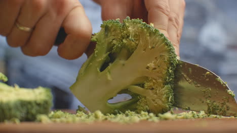 cut with a knife on a wooden board closeup broccoli in the kitchen. shred