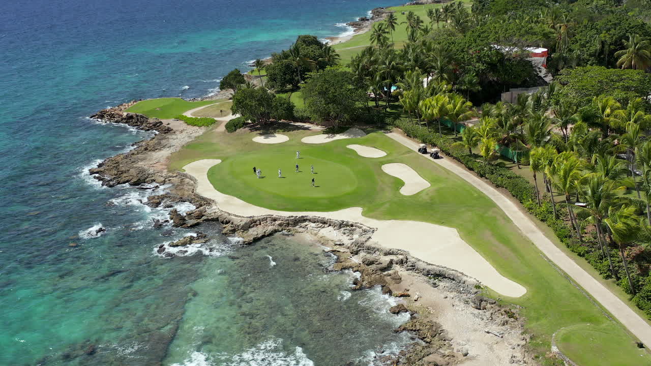 Aerial moving view of golfers on the green at a luxury ocean side golf course, La Romana, Dominican Republic