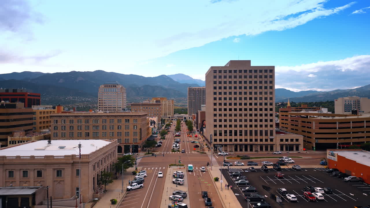 Colorado Springs, USA, 22 July 2025: Footage above the wide street with cars parked along. Mountains at backdrop. Scenery of Colorado Springs, Colorado, USA