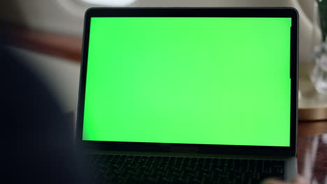 Closeup-hand-waving-green-laptop-screen.-Manager-videocalling-chroma-key-partner