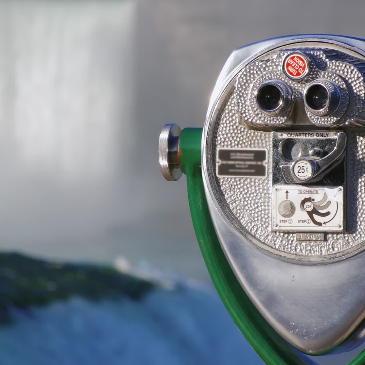 un visor binocular que funciona con monedas ubicado en las cataratas del niágara con vistas a las cataratas fuera de foco en el fondo