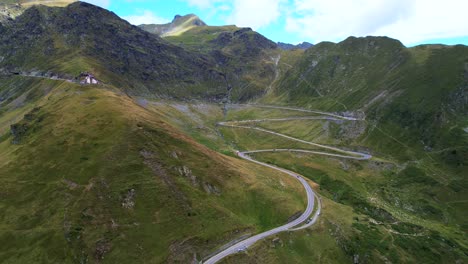 View-of-switchbacks-and-scenic-overlook-pull-off-on-Transfagarasan-Serpentine-Road-as-cars-drive-at-midday