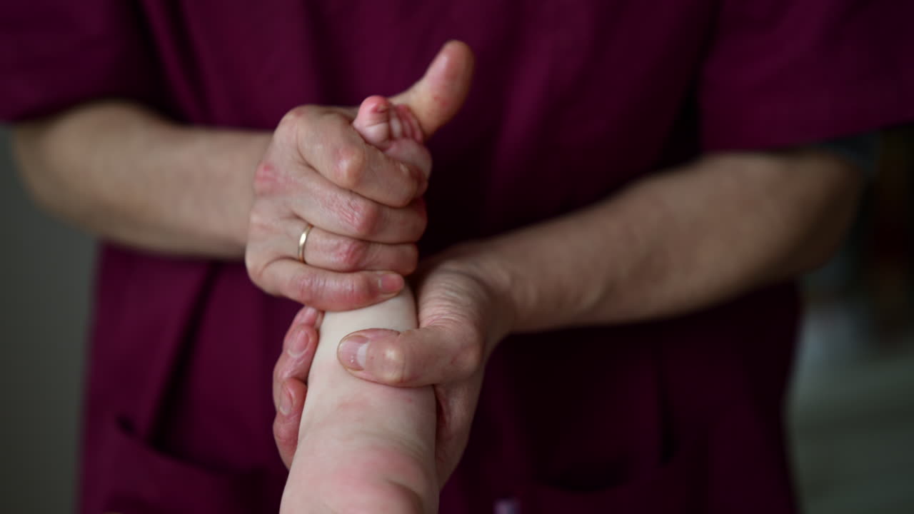 Close up of adult hands gently massaging a baby's foot and sole