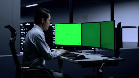 persona que trabaja en una computadora en una sala de servidores por la noche