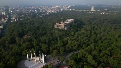 Aerial-view-tilt-down-establishing-over-the-Chapultepec-Castle-in-the-forest-and-the-Altar-to-the-Homeland-in-Mexico-City,-CDMX