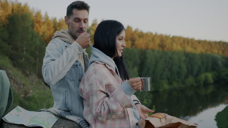 couple enjoying a picnic lunch by the river