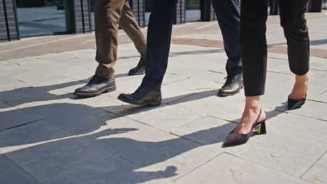 tres pares de piernas caminando por el pavimento en un día soleado de primer plano. pies personas caminando por la calle