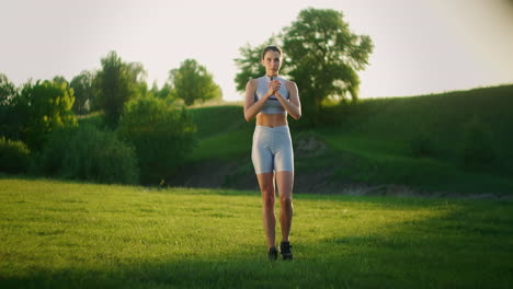 Una-Mujer-Se-Balancea-Parada-Sobre-Una-Pierna-Y-Se-Inclina-Hacia-Adelante-En-Un-Parque-En-El-Verano-Al-Atardecer