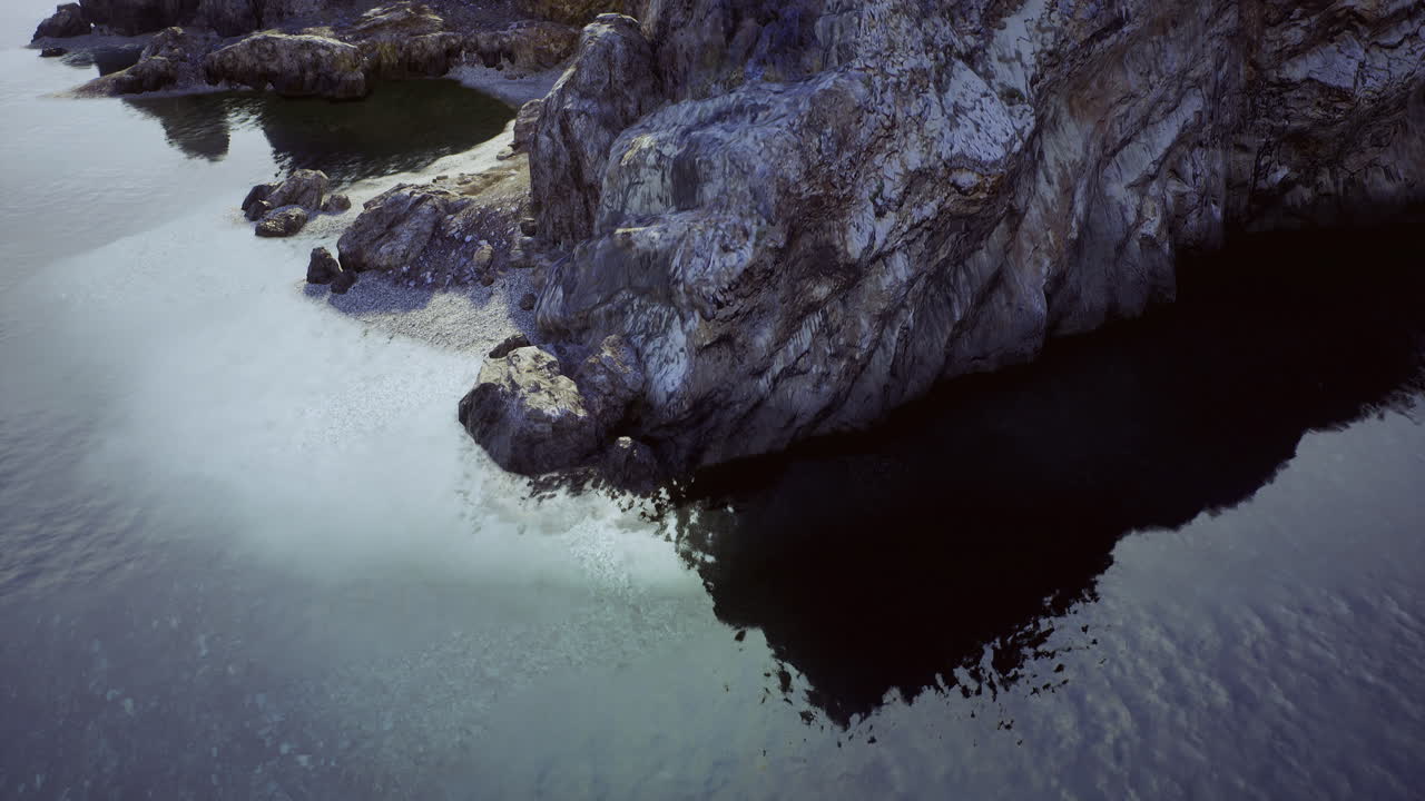 Serene waters reflect rugged cliffs at coastal location during golden hour