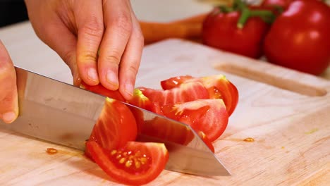 slicing tomatoes with a knife on wooden board