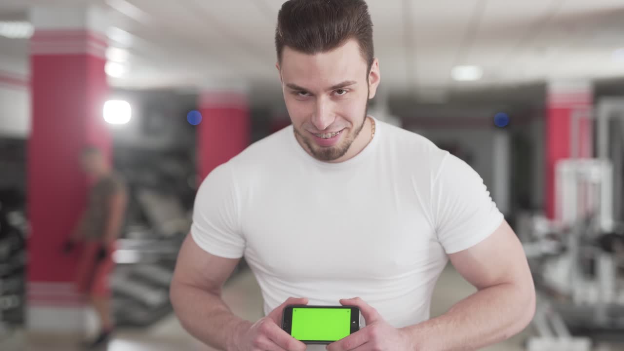 un entrenador físico se para y sostiene su teléfono