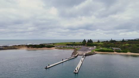 drone footage captures apollo bay's pier, ocean, and lush landscape under overcast skies, highlighting the serene coastal environment