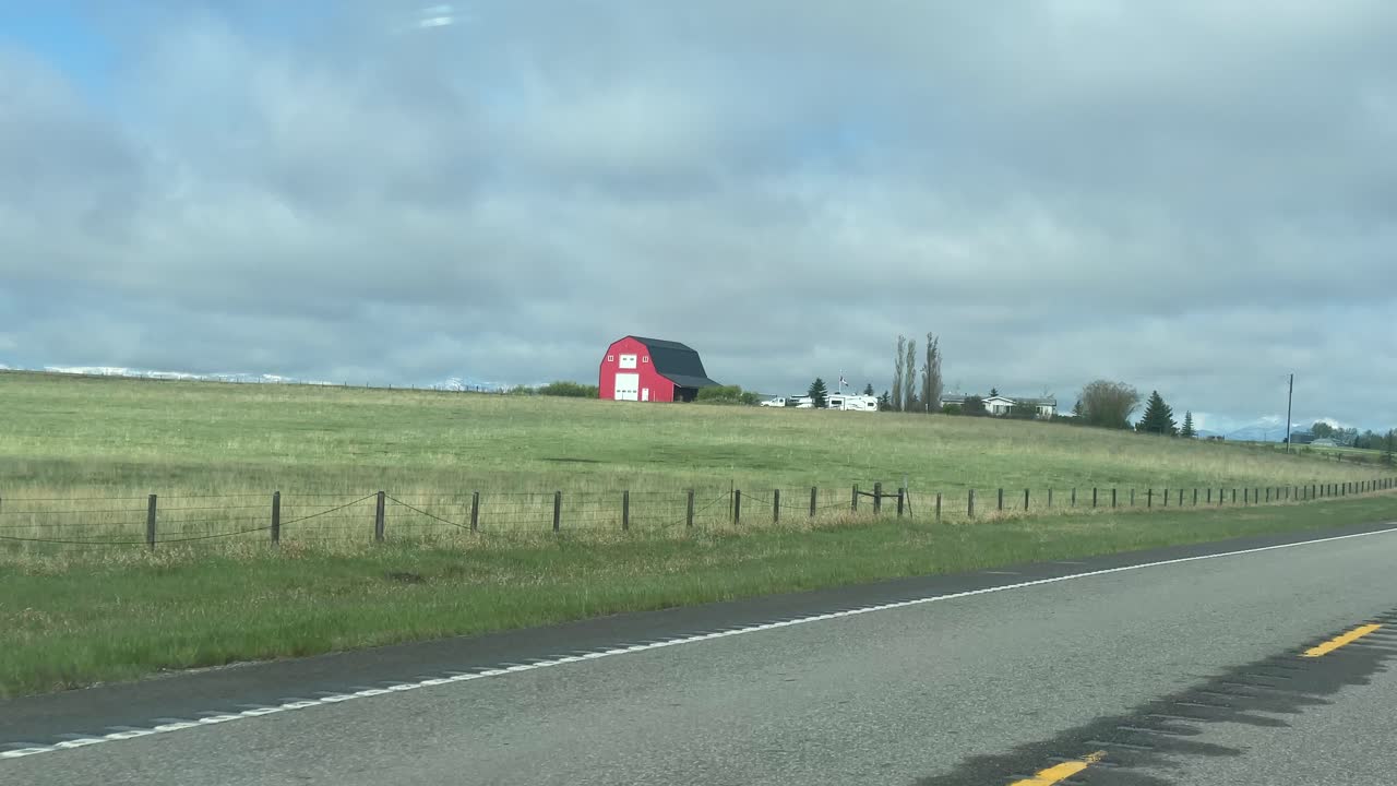 A red barn on the side of a rural highway