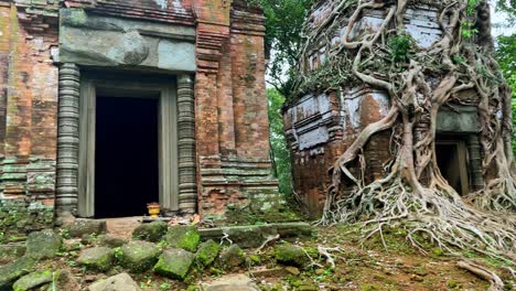 Truck-left-panoramic-view-of-the-Koh-Ker-temple-towers,-roots-invading-the-mossy-architecture,-UNESCO-heritage-site,-Cambodia