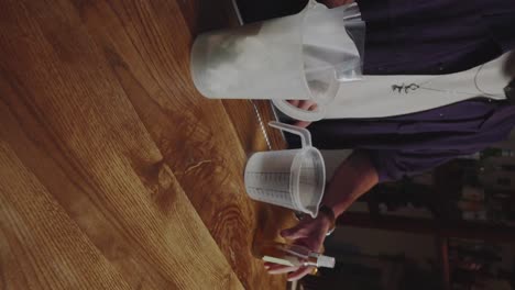 Man-spraying-malic-acid-in-plastic-jar-with-water,-stirring-slowly