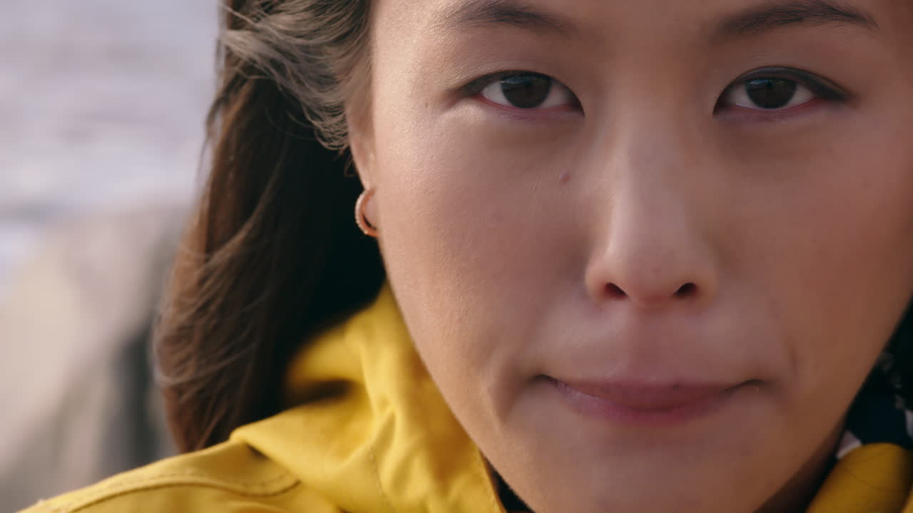 해가 지는 해변에서 자유를 탐험하는 심각한 독립적인 여성을 바라보는 해변에서 젊은 아시아 여성의 초상화