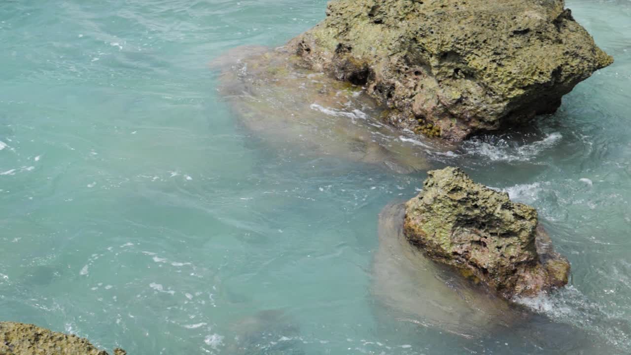 toma en cámara lenta de agua turquesa que rodea las rocas en el mar en la isla de asu, norte de sumatra, indonesia