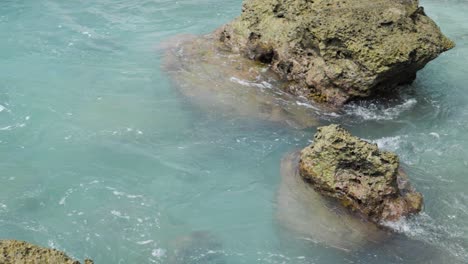 slow motion shot of turquoise water surrounding rocks in the sea at asu island, north sumatra, indonesia