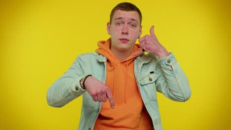 Cheerful-man-in-denim-jacket-looking-at-camera-doing-phone-gesture-like-says-hey-you-call-me-back