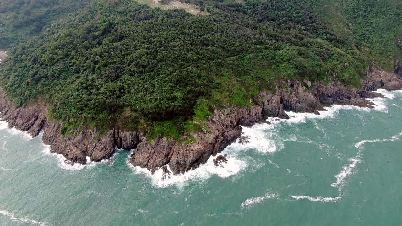 vista aérea de una isla rocosa irregular, rodeada de naturaleza verde y exuberante y agua de la bahía de hong kong