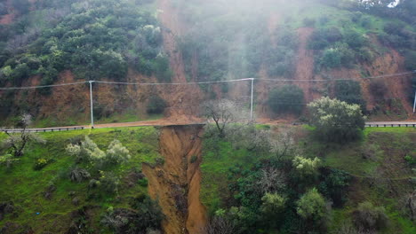 Aerial-view-of-a-mudslide-at-a-hillside-road-in-the-highlands-of-California,-USA