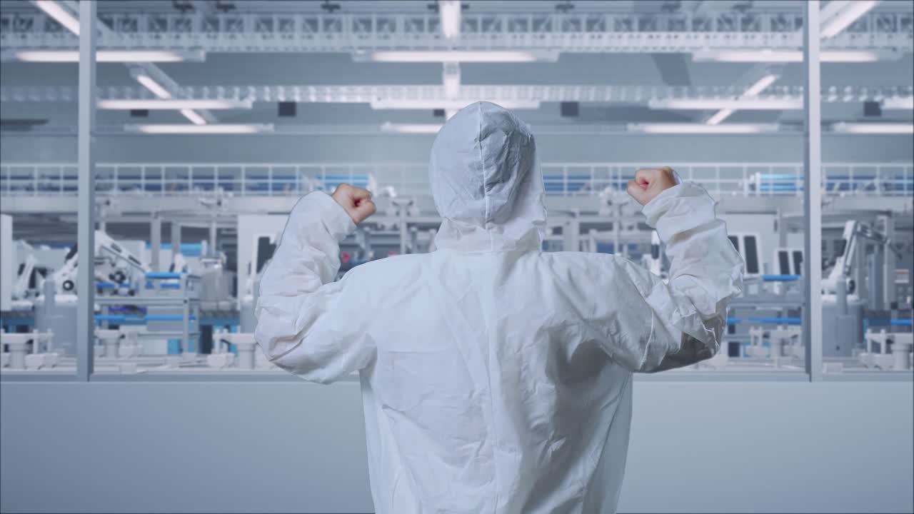 Back View Of Asian Male Scientist Celebrating The Succeed While Standing In Modern Lab Factory with Automated Robots
