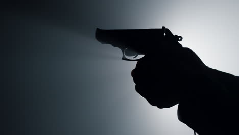 silueta de un hombre armando el gatillo de una pistola. un criminal desconocido armando el gatillo.
