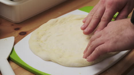 close-up, hands gently shaping pizza dough into a perfect crust on a cutting board