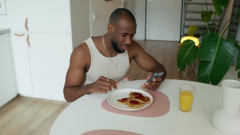 man taking a picture of his breakfast with his phone.