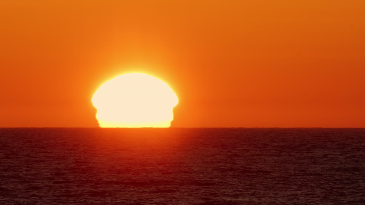 Midnight Sun Over the Sea Waves Close-Up. Sunrise distorted by atmospheric refraction. Lofoten Islands, Northern Norway