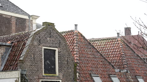 snow falling on brick stone roofs of typical architectures in the old city center of gouda in the netherlands