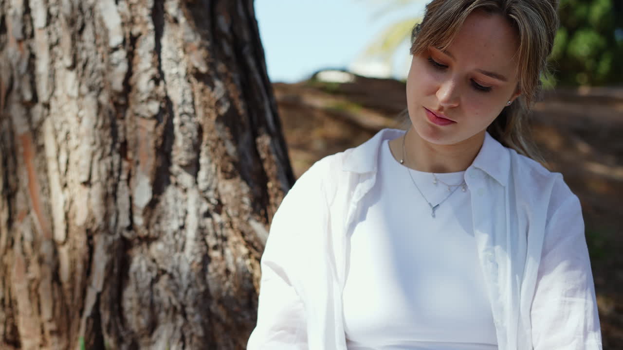 Woman sitting by a tree