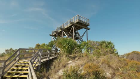 Panning-up-view-of-the-Hobe-Mountain-observation-tower,-site-of-WWII-army-training-facility-at-Jonathan-Dickinson-State-Park-in-Florida