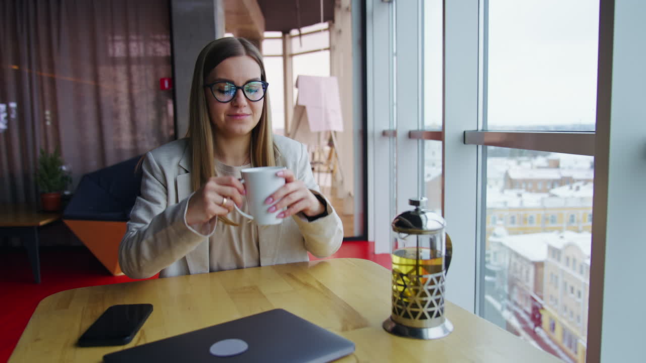 Woman enjoying a drink and looking outside from modern office