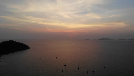 Sunset-over-the-ocean-with-boats-and-mountains-in-the-background