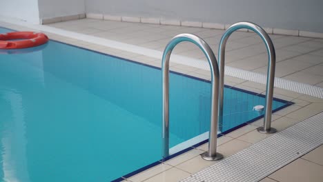 piscina cubierta con escalera de metal y anillo de salvamento