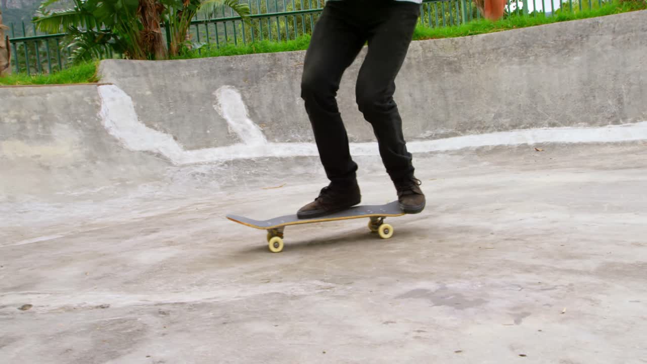 sección baja de un joven practicando truco de skateboard en la rampa en el parque de skateboard 4k
