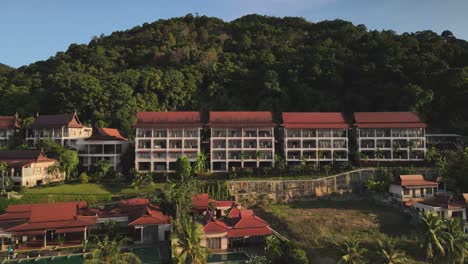 Reversing-aerial-shot-of-a-large-resort-on-the-coast-of-rainforest-island-Koh-Chang,-Thailand