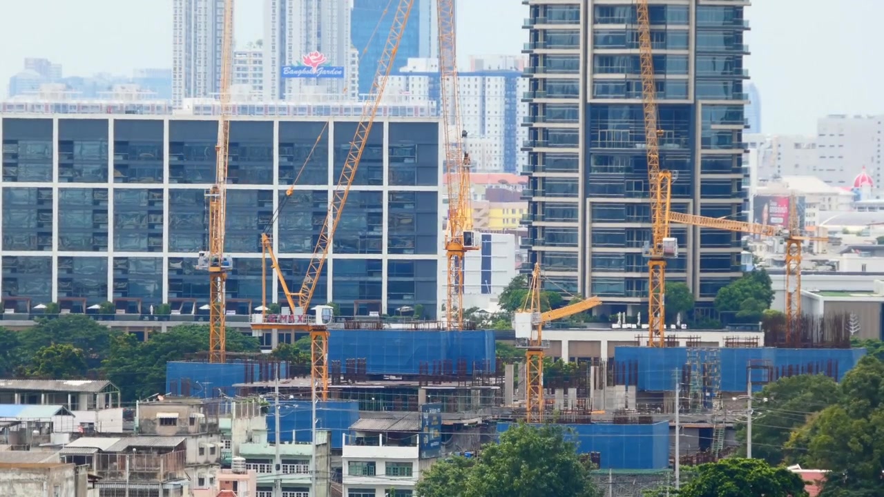 都市の建設現場でタワークレーンが稼働し、継続的な建設の進捗と現代都市の発展を捉えたタイムラプス映像。