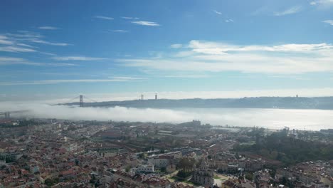 aerial view: lisbon's coastal dwellings, 25 april bridge, and foggy allure—a captivating daytime canvas in portugal