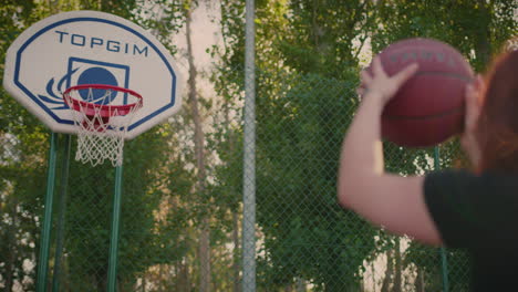 basketball court redhead girl shoots ball in slow motion and scores close shot