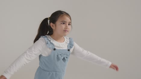 흰색 배경에 대해 웃고 팔을 휘두르는 활동적인 소녀의 스튜디오 초상화