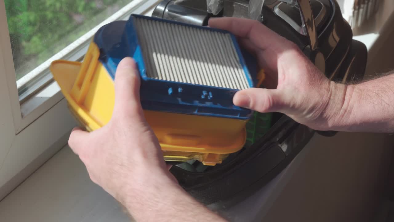 las manos masculinas sacan el filtro de la aspiradora y comprueban su condición. filtro muy sucio en la aspiradora, reemplazo urgente.