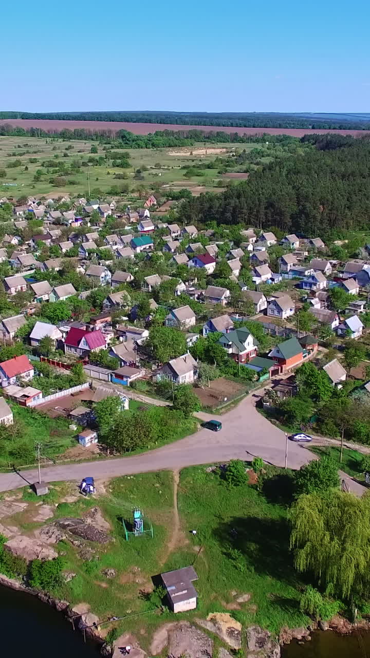Sunny countryside landscape on a beautiful clear daytime. Lovely picturesque village locating on the bank of the river. View from top. Vertical video